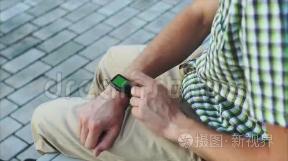 穿着休闲的男士双手使用绿色屏幕的现代智能手表