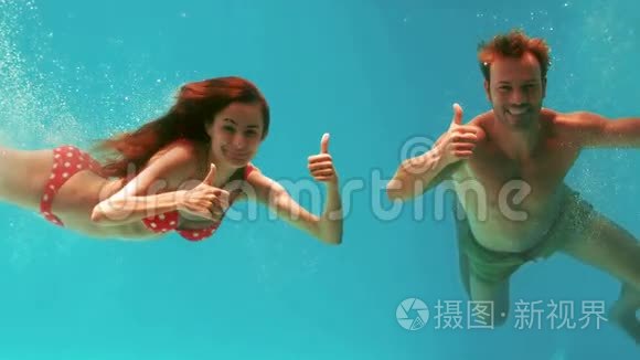 一对拇指向上的夫妇在水下游泳视频