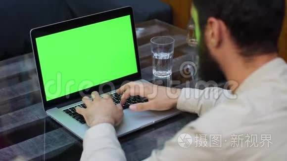 男人用绿色屏幕在笔记本电脑上工作