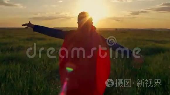 穿着超人斗篷的男孩跑在田野里，看着夕阳