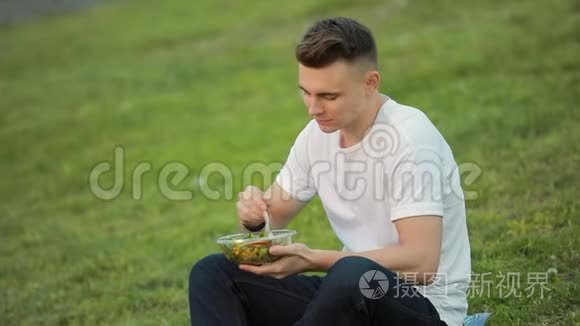 坐在草地上吃沙拉的人