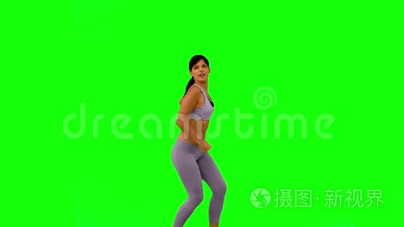 运动女性在绿色屏幕上跳跃和摆姿势