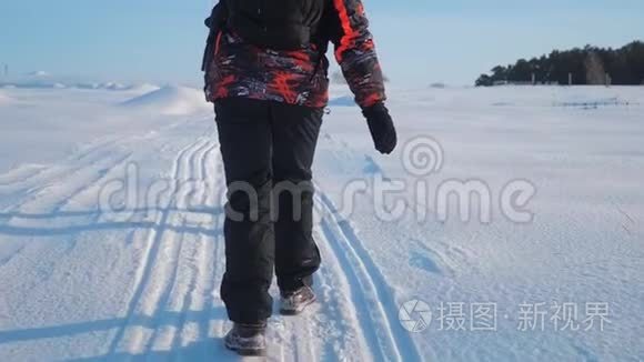 团队合作。 男游客摄影师在冬天乘三脚架爬山顶山顶岩峰群去雪