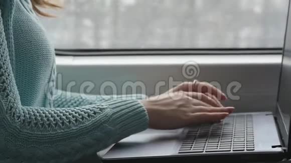 年轻女孩坐火车，用笔记本。 在铁路上，女性手按键盘打字视频的预览图