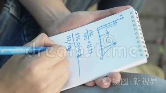 人手在纸笔记本，图表上用蓝色记号笔画出数学任务.. 夏季