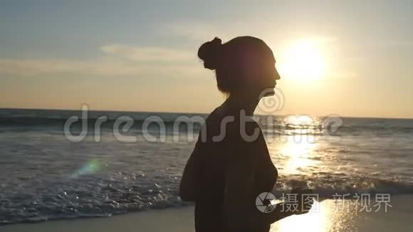 日出时沿着海岸慢跑的女孩。 日落时在海边奔跑的年轻女子剪影。 女性