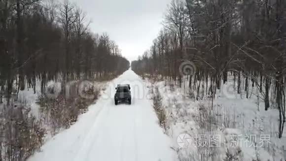 越野车6x6在雪地森林的冬季道路上行驶，后景