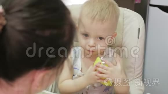 妈妈用勺子喂她的小儿子。 妈妈在家里给她可爱的孩子提供健康的食物。 快乐的小男孩