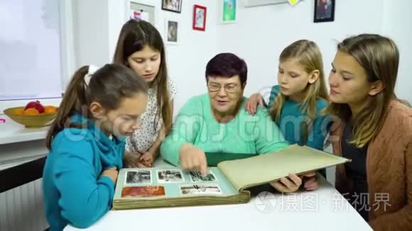 祖母和四个孙女在家看旧相册视频