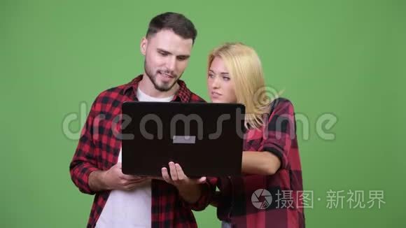 年轻的幸福夫妇一起用笔记本电脑微笑