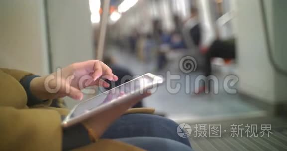 地铁列车上使用平板电脑的女性