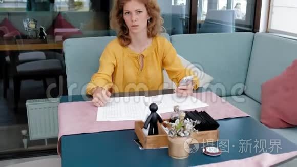 美丽的年轻女子在咖啡馆里浏览文件