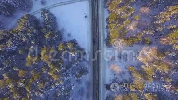 一辆车在乡村公路上穿过冬季森林。 从无人驾驶飞机俯视。 穿过森林的道路的鸟瞰图