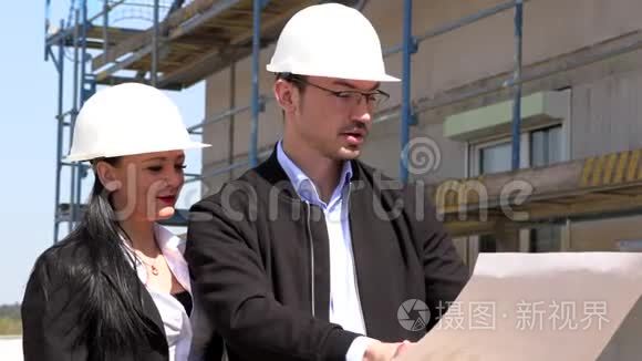 两名戴白盔的建筑师在工地上讨论一项计划