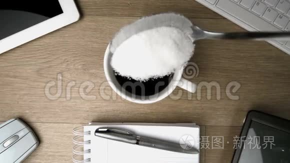 茶匙里的糖掉进桌上的一杯咖啡里