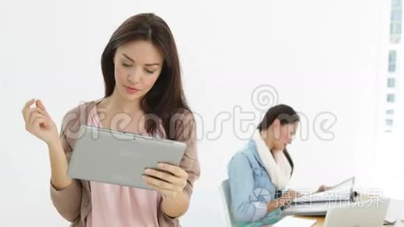 创意女商人使用平板电脑的同事在她身后