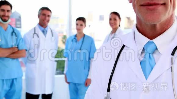 医生在镜头前微笑，身后有团队