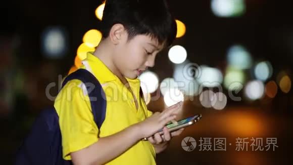 亚洲小孩在夜间灯光背景下玩智能手机