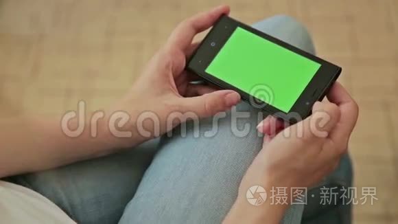 漂亮的女人手里拿着绿色屏幕显示的智能手机