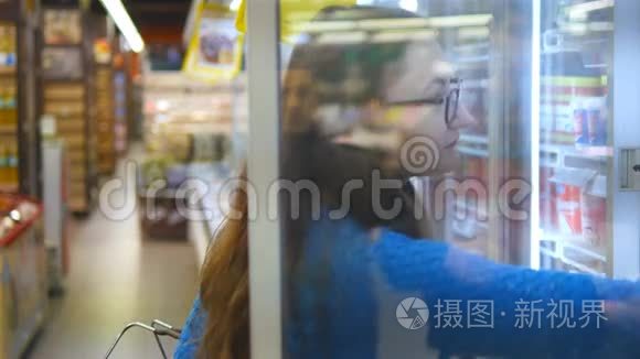 带着购物车在冷藏区的超市里买奶制品或冷藏食品的年轻女子