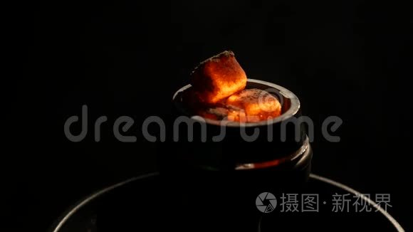 在黑暗的特写镜头中，热煤在钩子碗里。 黑色背景