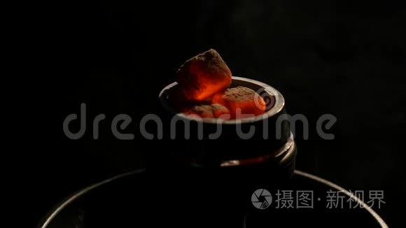 在黑暗的特写镜头中，热煤在钩子碗里。 黑色背景