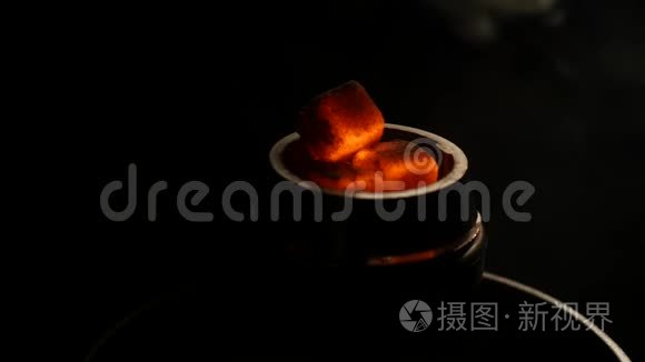 在黑暗的特写镜头中，热煤在钩子碗里。 黑色背景