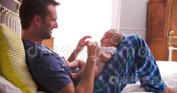 父亲在床上玩新生儿女儿视频