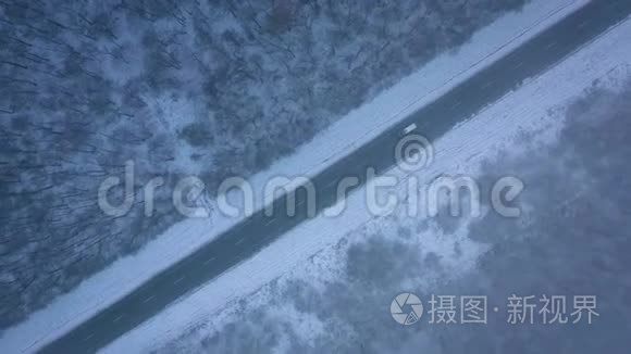 暴风雪中穿过冬季森林的道路上的交通鸟瞰图