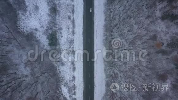 暴风雪中穿过冬季森林的道路上的交通鸟瞰图