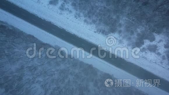 暴风雪中穿过冬季森林的道路上的交通鸟瞰图