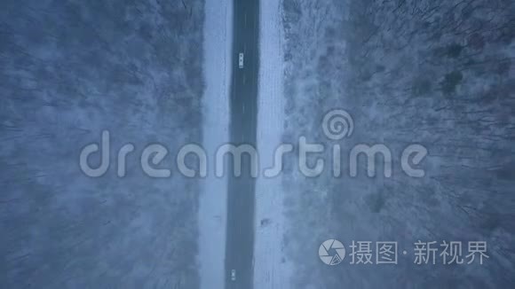 暴风雪中穿过冬季森林的道路上的交通鸟瞰图