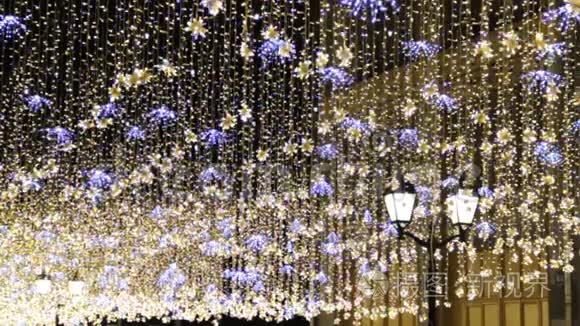 圣诞节和新年假期晚上在城市街道的户外照明。金光闪闪，挥舞着花环
