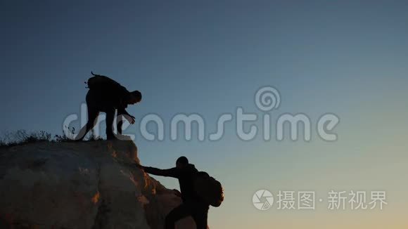 两个男子协同游客爬上一座山。 徒步旅行者徒步旅行冒险登山日落攀登