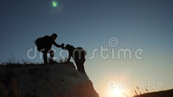 两个男子协同游客爬上一座山。 徒步旅行者徒步旅行冒险登山日落攀登