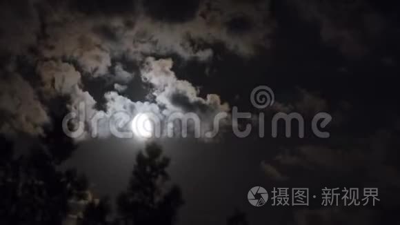 满月通过乌云和树木在夜空中移动。 时光流逝。