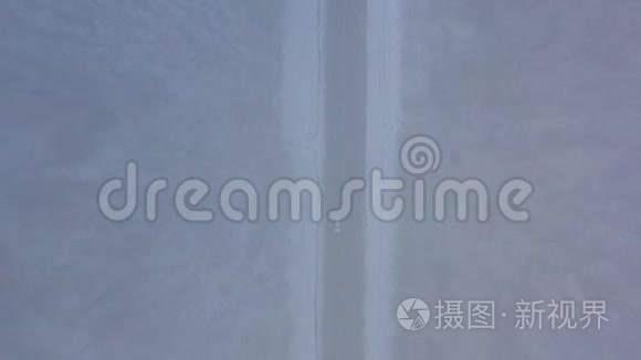 暴风雪中穿过冬季森林的道路上的交通鸟瞰图