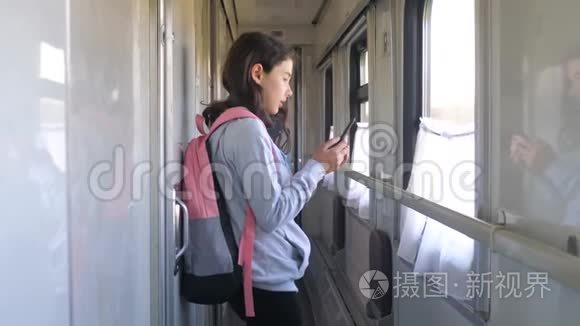 小女孩走在火车车厢生活方式车上，背包和智能手机。 旅游运输铁路