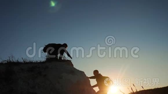 两个男子协同游客爬上一座山。 徒步旅行者徒步旅行冒险登山日落攀登