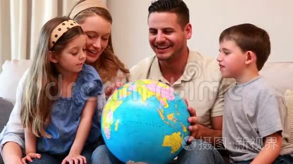 幸福的年轻家庭坐在沙发上看地球仪