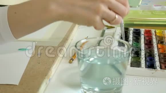 坐在桌旁的一个红发小姑娘画着颜料