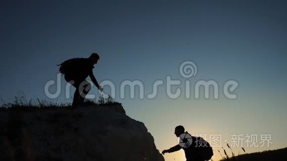 两个男子协同游客爬上一座山。 徒步旅行者徒步旅行冒险登山日落攀登