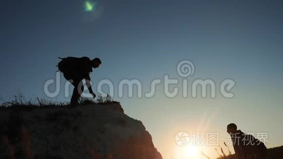 两个男子协同游客爬上一座山。 徒步旅行者徒步旅行冒险登山日落攀登