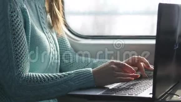 女性手在火车上的笔记本电脑键盘上打字。 女人在铁路上旅行时和朋友聊天。 少女视频的预览图