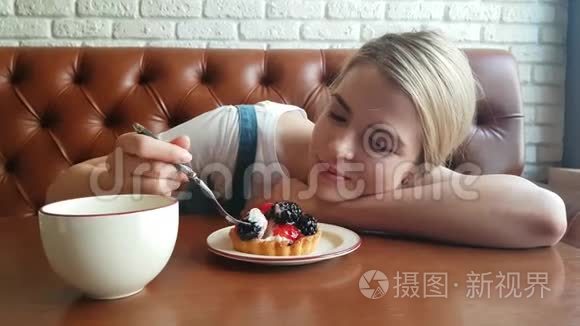 年轻的女人在吃黑莓蛋糕