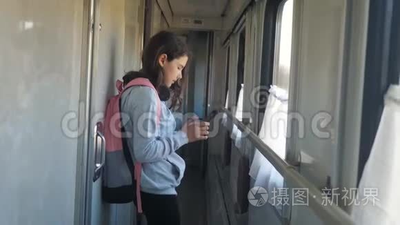 小女孩走在火车车厢里，带着背包的生活方式和智能手机。 旅游运输铁路