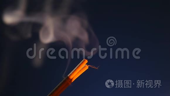 在黑色的背景上，用烟雾把燃烧着的香枝合上