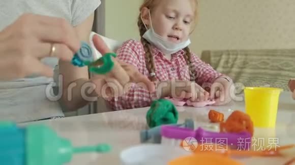 一个年轻的女人和一个女孩用塑料制成牙齿，把牙齿插入玩具下巴，扮演一个牙医，母亲和