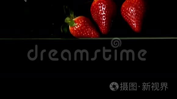 草莓落在黑色背景的水里视频