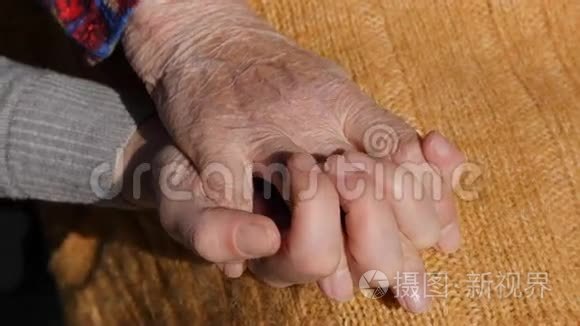 一只年轻的雌性手安慰着一双年迈的奶奶的双手